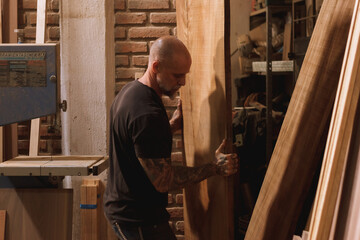 Hombre maduro mexicano trabajando carpintero en taller con madera tabla sierra martillo 