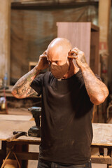 Hombre mexicano maduro carpintero en taller con madera trabajando con mascara facial pandemia