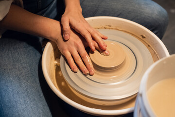 master class on sculpting a pot in an art workshop. the girl behind the Potter's wheel makes a blank with her hands