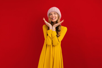 Happy beautiful young woman in a warm hat on her head, on a red background