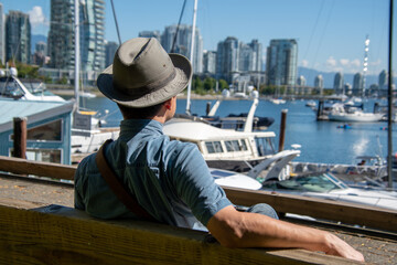 サングラスをかけたアジア人男性が海辺のベンチで休む様子　　　バンクーバー　ブリティッシュコロンビア　カナダ
