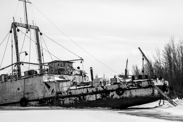 Fototapeta na wymiar Abandoned white ship frozen in ice near lighthouse