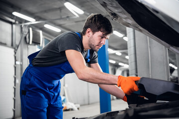 Repairer opens the hood and checks the car engine