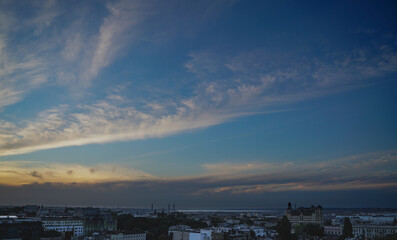 Obraz premium Sunset with stripes of white and orange clouds over the city with the bay