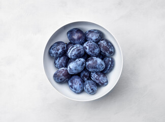 plums in bowl on white rustic background