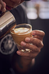 Barista making cup of coffee latte in coffee shop in close up style