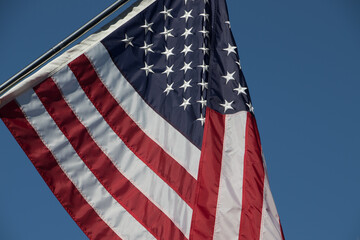Closeup of the American flag flying in the breezes with a brilliant blue sky background
