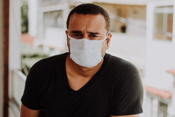 Sick brazilian man wearing medical mask at home during Coronavirus outbreak