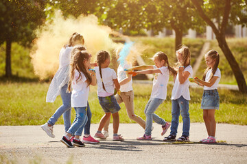 Obraz premium Happy smiling girls have fun using Holi colors, in the summer at sunset