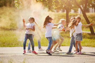 Fototapeta premium Happy smiling girls have fun using Holi colors, in the summer at sunset