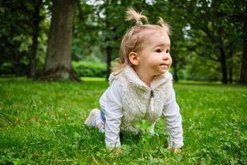 A joyful child crawls the grass in the park