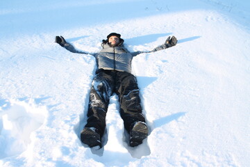 Fototapeta na wymiar Happy young man lying in snow in cold weather