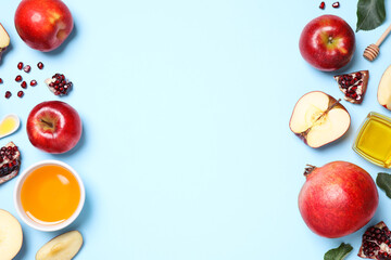 Naklejka na ściany i meble Honey, apples and pomegranates on light blue background, flat lay with space for text. Rosh Hashanah holiday