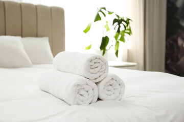 Clean white towels on bed at home