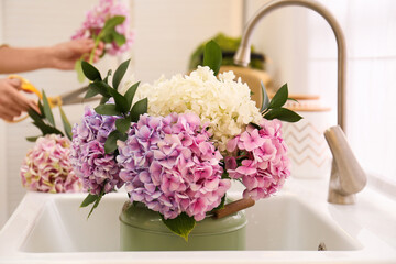 Closeup view of woman making bouquet, focus on beautiful hydrangea flowers in sink