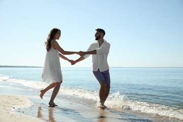 Fototapeta na wymiar Happy young couple having fun on beach near sea. Honeymoon trip