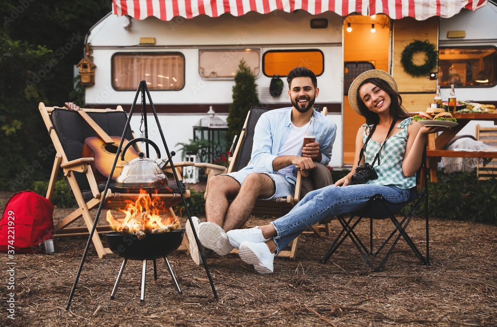 Sticker Happy couple resting near trailer. Camping season