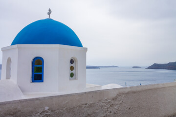 Classic blue dome from O&iacute;a, Santorini Island. Ocean view in the background on cloudy day with copy space.