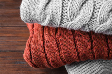 Fototapeta na wymiar Stack of folded warm sweaters on wooden background, closeup