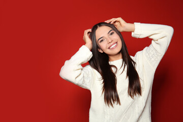 Naklejka premium Pretty woman wearing warm sweater on red background