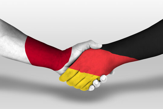 Handshake between germany and japan flags painted on hands, illustration with clipping path.