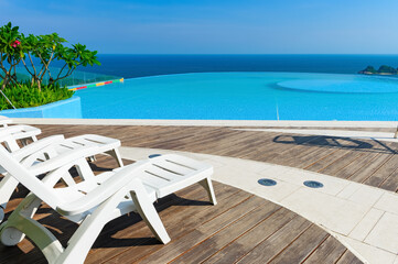 sun loungers in front of a swimming pool with the ocean at the far end