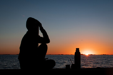 silhouette of a woman on a pier at sunset