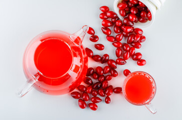 Scattered cornel berries from a bowl with drink flat lay on a white background