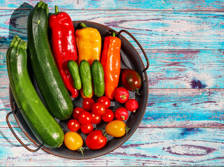 fresh vegetables on the table
Fresh vegetables in an iron dish lie on an old wooden table on the left with space for text on the right, top view close-up.