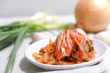 Kimchi is placed in a white plate with a fork on its side.