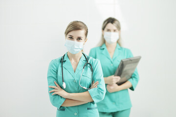 Two female doctors in medical masks looking at the camera. Stethoscope on neck