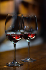 Pair of wine glasses with red wine and wine barrels reflection. Wine tasting in a wine cellar. Vineyard in Mendoza region, Argentina