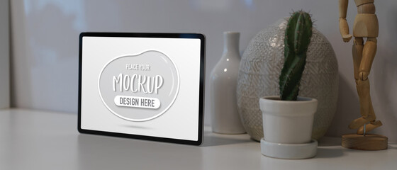 Workspace with mock up tablet, cactus pot and decorations on white table