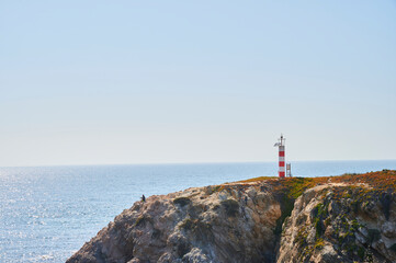 Fototapeta na wymiar man seated over the cliff near a lighthouse