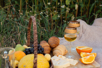 fruits, cheese, wine and croissants: picnic on the grass