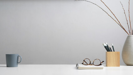 Study table with stationery, eyeglasses, notebook, mug, decoration and copy space in home office
