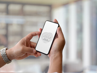 Male hands holding mock up smartphone in blurred background