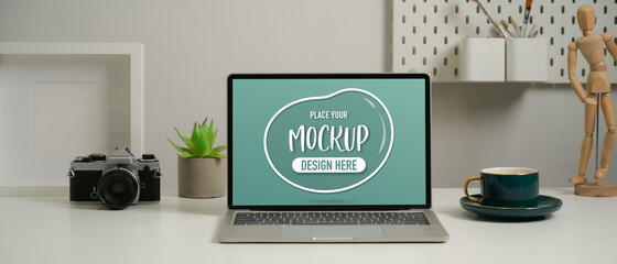 Mock up laptop on worktable with camera, coffee cup and decorations on worktable