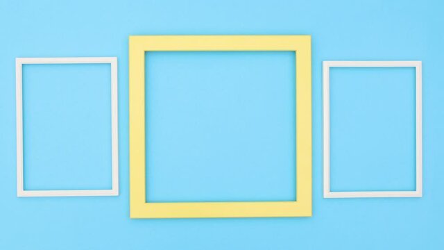 Two white frames moving around yellow big frame on blue theme. Stop motion 