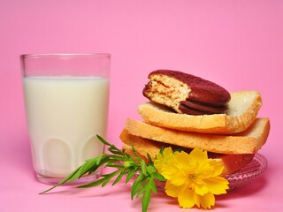 Dry rusk bread, choco pie chocolate and a glass of milk isolated on pink background. Healhty breakfast menu