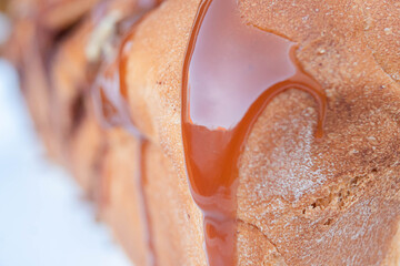 Exquisite homemade trenza bread with milk caramel on top on a white plate in close up.