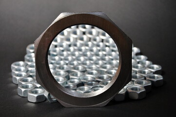 Metal nut and many small nuts on a dark background