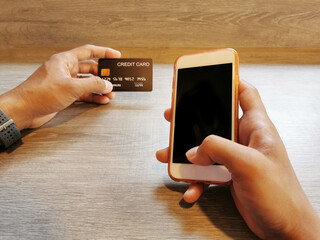 Selected focus of man's hand holding the smartphone for online shopping and pay by credit card. ...