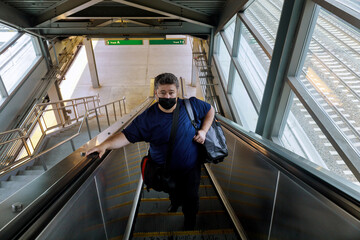 Traveling during in the pandemic man wearing protective face mask on standing on an escalator the railway station