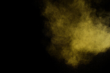 Yellow powder explosion on black background. Colored powder cloud. Colorful dust explode. Paint  Holi.