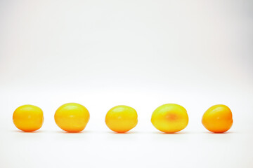 Isolated row of yellow ripe tomatoes over on white background
