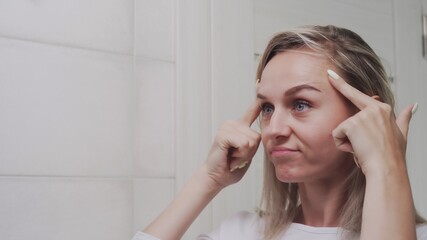 Close up of Frustrated girl looks at her face in the bathroom mirror