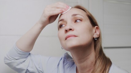 Fototapeta premium Adult woman applying lotion and looking in mirror enjoy natural beauty and healthy