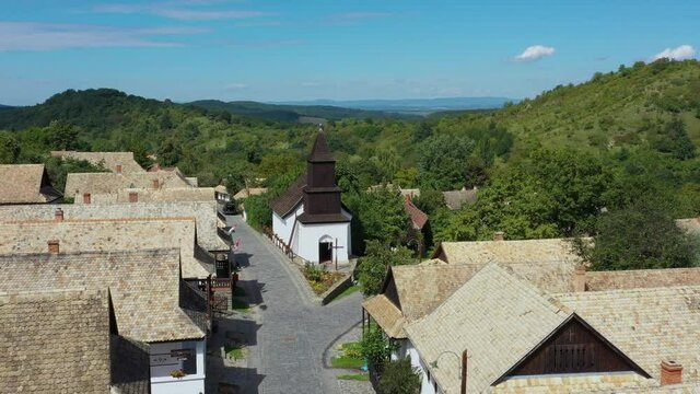 Drone flies over the historical streets of Holloko, Hungary in the afternoon. Drone looks down and goes forwards