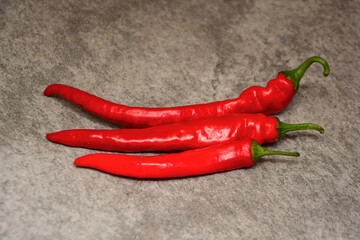 Fresh organic red chili peppers close-up on a dark gray slate, stone or concrete background. 